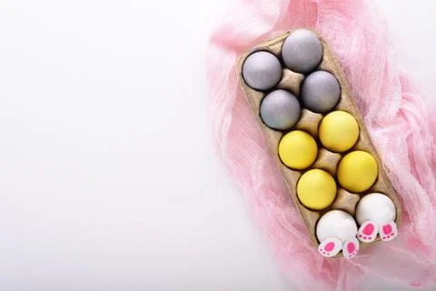 Yellow and blue Easter eggs, Easter Bunny in cardboard box on pink fabric on  Stock Photos