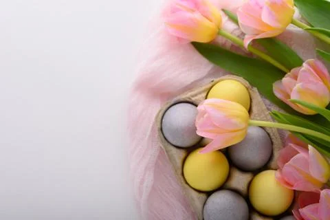 Yellow and blue Easter eggs in cardboard box on pink fabric on white backgrou Stock Photos