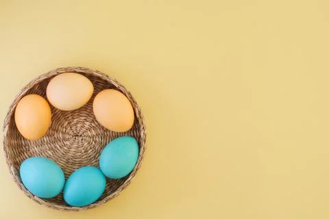 Yellow and blue easter eggs in basket on yellow background with place for text Stock Photos