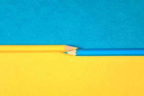 Yellow and blue pencil on universal two tones paper background. two multic... Stock Photos