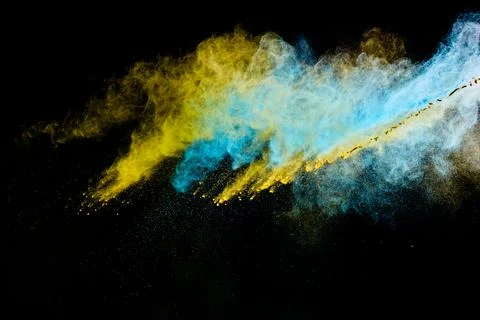 Yellow and blue powder exploding against black background Foto stock