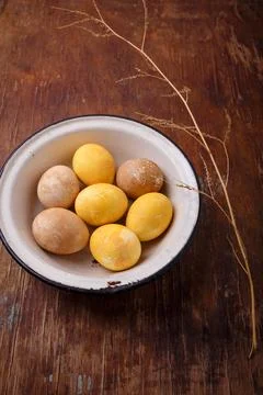 Yellow and brown Easter eggs in white bowl on wooden table. Spring holiday Stock Photos