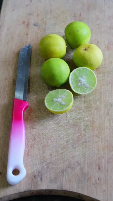 Yellow and green lemons with half slices and a knife on a wooden cutting board Stock-Footage 332228337