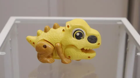 Yellow and Orange Plastic Dinosaur Toy Placed Gently on Glass Table Stock Footage 321436677