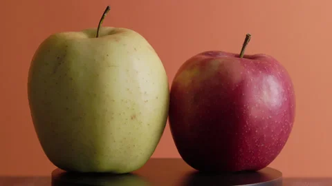 Yellow and Red apples rotate around an axis on an orange background Stock Footage 330687286