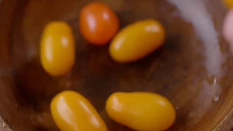Yellow and red cherry tomatoes in a wooden bowl, falling in slow motion 動画素材 121934262