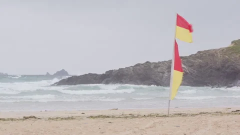 Yellow and red lifeguard flags flapping in strong wind on Cornwall beach Stock Footage 278450840