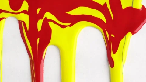 Yellow and red mixed drops of paint flow down on white canvas. Abstract art.. Video stock 250163675