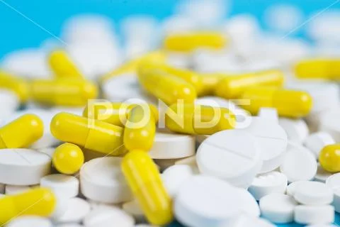 Yellow and white pills or capsules on a blue background Stock Photos