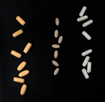 Yellow and white pills in pack on black background Stock Photos
