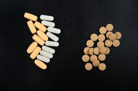 Yellow and white pills in pack on black background Stock Photos