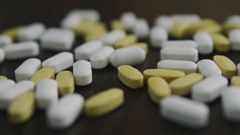 Yellow and white pills on the table, slowly approaching focus on macro close up Stock Footage 126271908