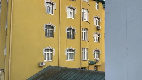 Yellow apartment building facade with white windows and air conditioners Stock Footage 341830092