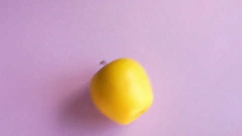 The yellow apple is rolling on the purple table Stock Footage 112265749