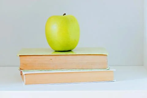 A yellow apple sitting on top of a stack of books Stock Photos