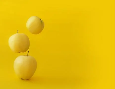 Yellow apples on a yellow background in gravity Stock Photos