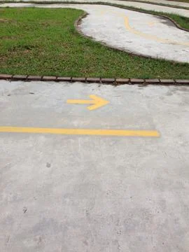 Yellow Arrow Painted On Concrete Path Stock Photos