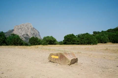 Yellow arrow on a stone, specifying a direction in mountains Stock Photos