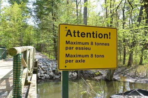 Yellow attention maximum 8 tons per axle sign in French and English on bridge Stock Photos