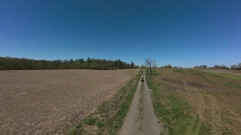 Yellow ATV driving down a narrow dirt trail through wide countryside fields Video stock 341818397