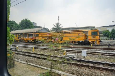A yellow automatic railway track maintenance machine vehicle parked Stock Photos