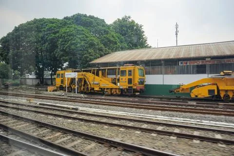 A yellow automatic railway track maintenance machine vehicle parked Stock Photos