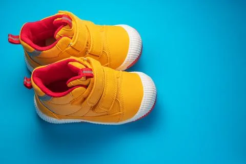 Yellow baby shoes. Kids sport sneakers isolated on blue background Stock Photos