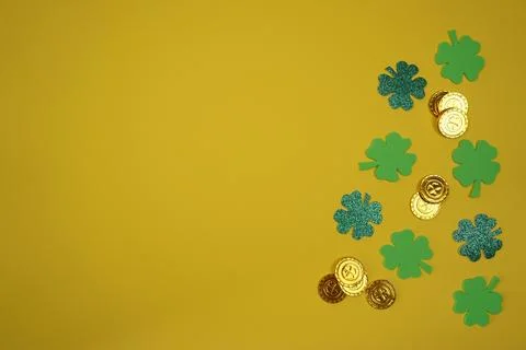 On a yellow background are four-leaf clover and gold coins Stock Photos