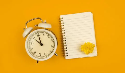 Yellow background with copy space notepad and alarm clock, time managment con Stock Photos