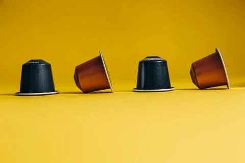 Yellow background with four coffee capsules Stock Photos