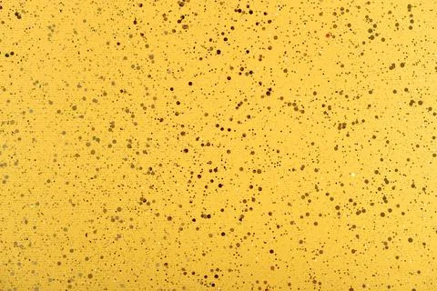 Yellow background with golden sparkles. Stock Photos