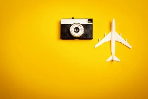 Yellow background with an old camera and a toy airplane 스톡 사진