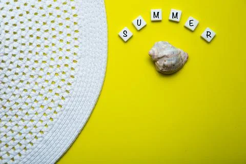 On a yellow background there is a shell and the word summer is written above it Stock Photos