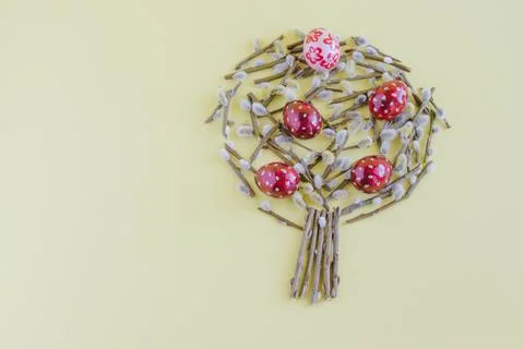 On a yellow background willow tree, lined with branches and colorful Easter e Stock Photos