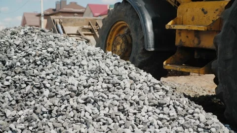 Yellow backhoe loader moving through construction site near large pile of g.. Stock Footage 334605311