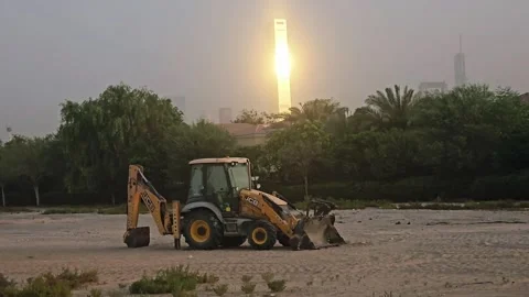 A yellow backhoe loader vehicle parked on an empty dirt construction field with Stock Footage 338308255