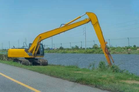 Yellow backhoe working riverside and on the roadside Foto stock