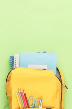 Yellow backpack with notebooks and study supplies. Stock Photos