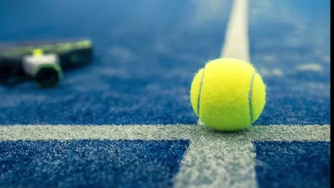 Yellow ball on floor behind paddle net in blue court outdoors. Padel tennis Stock Footage 202286228