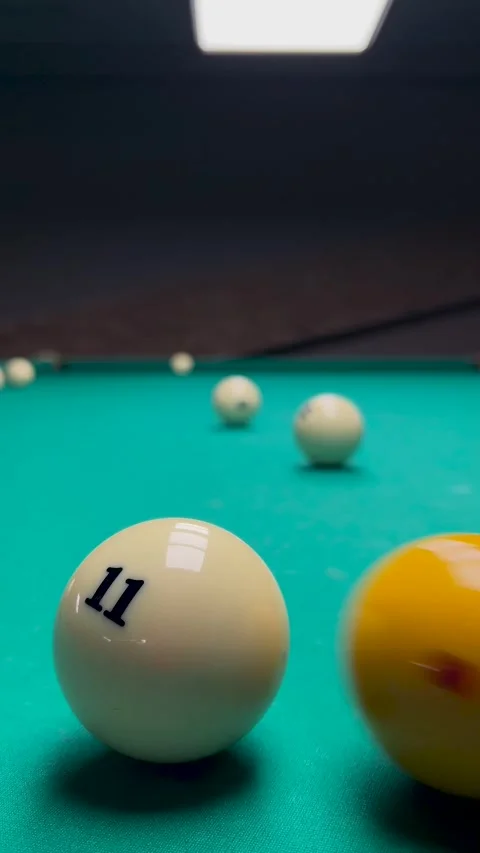 Yellow ball with red dot hits white ball with number 11 on pool table Stock Footage 304767990