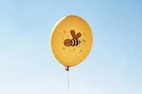 Yellow balloon with bee pattern on blue sky background Stock Photos