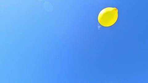 Yellow balloon floating and flying against clear blue sky Stock Footage 321763918