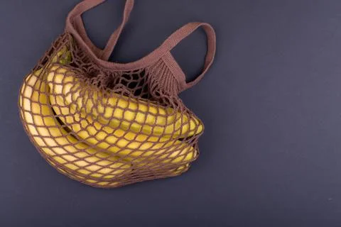 Yellow bananas in a beige string bag on a black background, Copy space Stock Photos