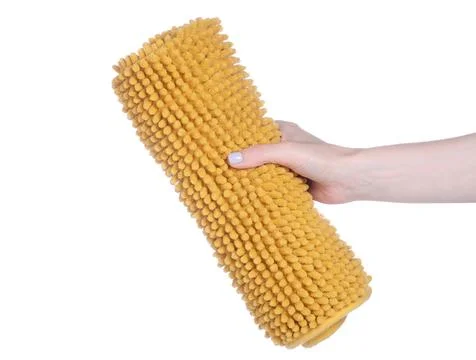 Yellow bath mat in hand Stock Photos