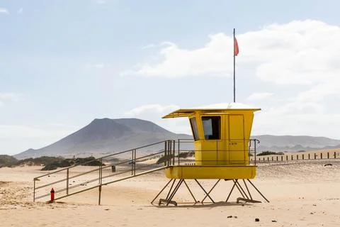 Yellow beach safety flag warning. Lifeguard tower. Stock Photos