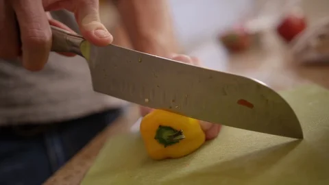 Yellow bell pepper being sliced in kitchen by male hands Stock Footage 123739156
