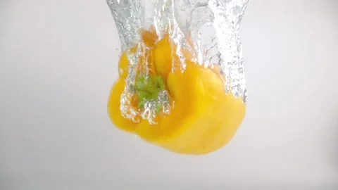 Yellow bell pepper fall into the water with splashes and bubbles in slow motion Stock Footage 144445757