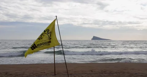 Yellow Benidorm SOS warning flag hanging on post waving at the beach Stock Footage 227159490