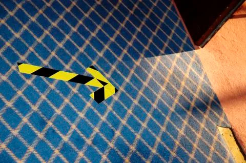Yellow black arrow on a patterned carpet, note, direction, nrw, nordrhein wes Stock Photos