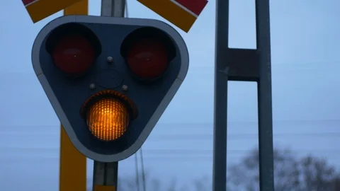 A yellow blinking light at a train track intersection signaling caution - Video stock 122191185